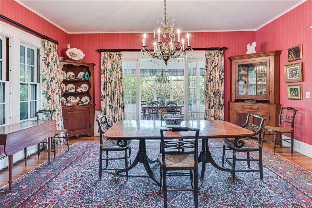 Dining room with red striped walls, a large wooden table, floral curtains, and a chandelier.