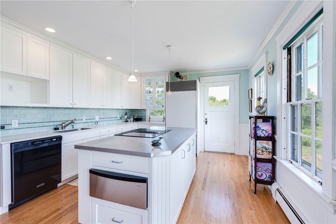 Bright kitchen with a white island, pale aqua tile backsplash, and wide windows.
