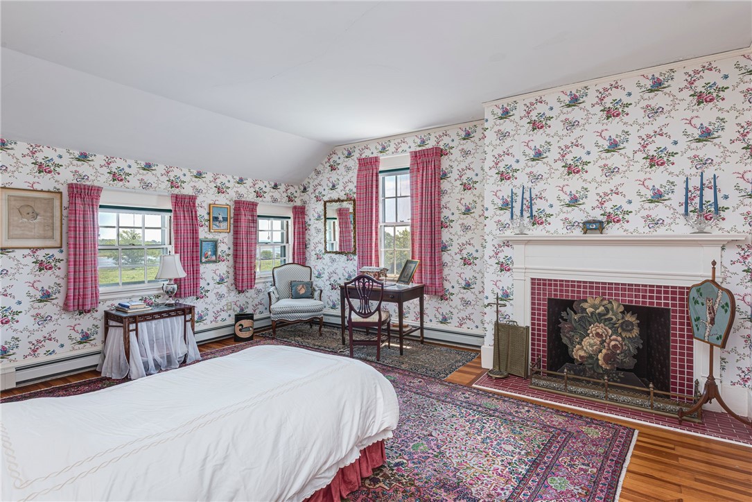Bedroom with floral wallpaper, a white bed, and a fireplace with red tile surround.