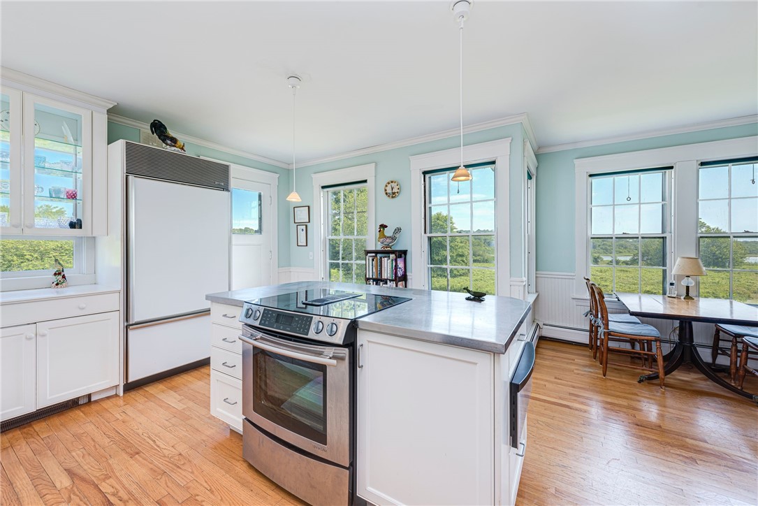 Bright white kitchen with a stainless-steel range, large island, and windows overlooking wetlands and water.