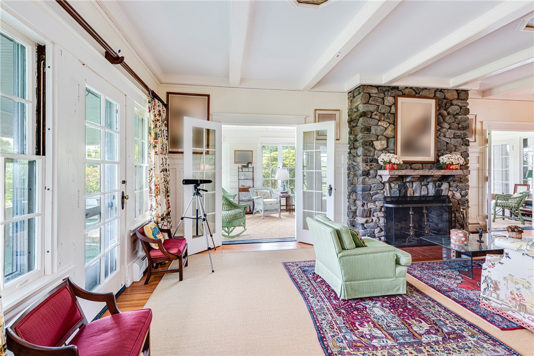 Living room with a stone fireplace, French doors, pale green seating, and patterned rugs.