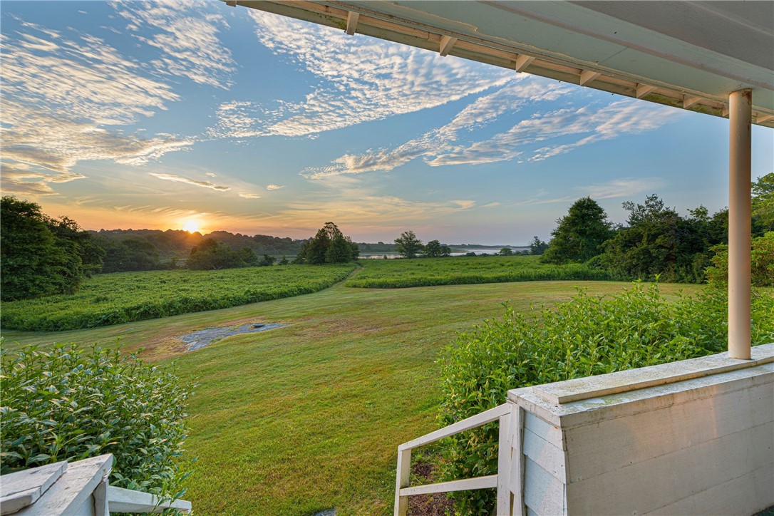 Porch overlooking a lawn, marsh, and distant water at sunset