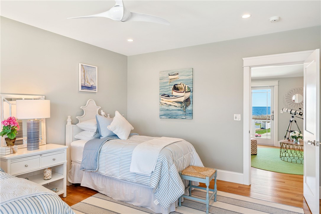 Bedroom with blue-and-white striped bedding and ocean visible through the doorway.