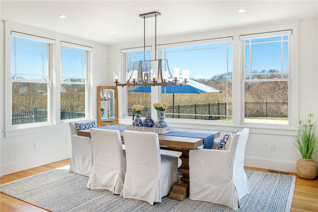 Bright dining room with a wooden table and large windows overlooking a fenced patio.
