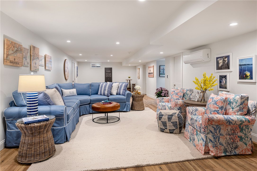 Staged living room with a blue sectional, floral armchairs, and a large cream rug.