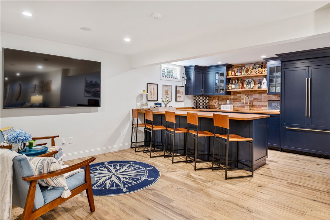 Entertainment room with a navy-blue bar, brick backsplash, wood counter, and compass rose rug.