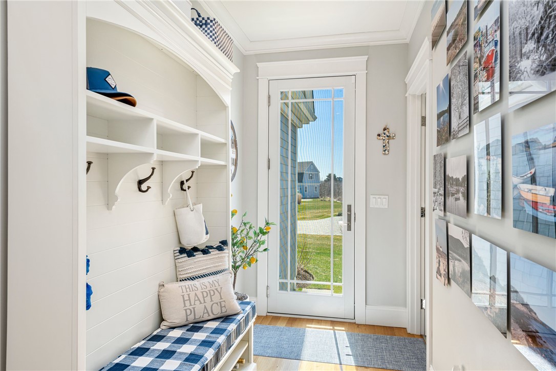 Bright entryway with a built-in mudroom bench, plaid cushions, and a glass door to the lawn.