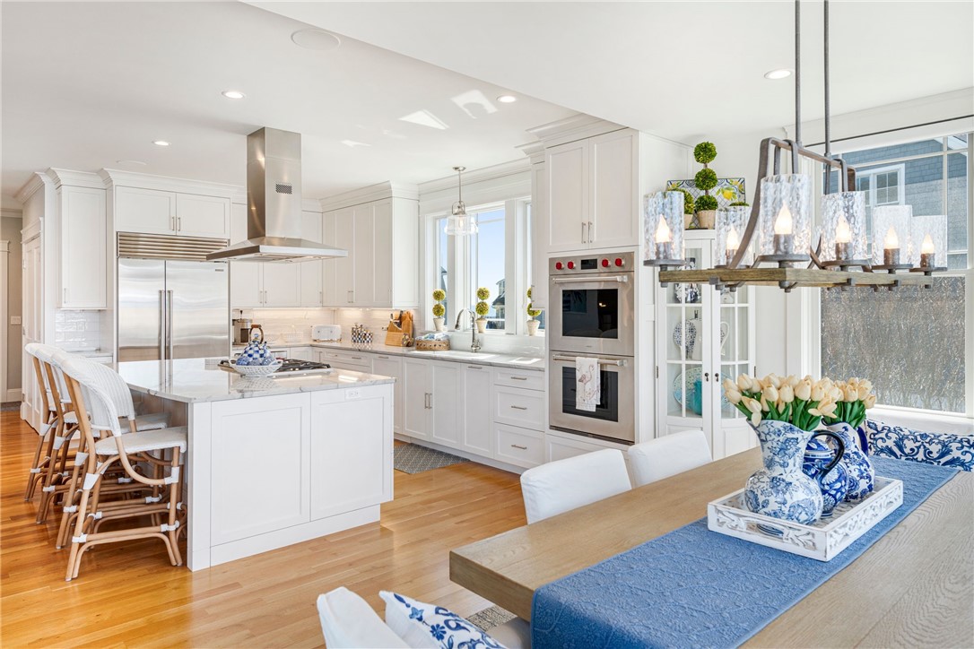Bright white kitchen with a large island, stainless-steel appliances, and adjoining dining table.