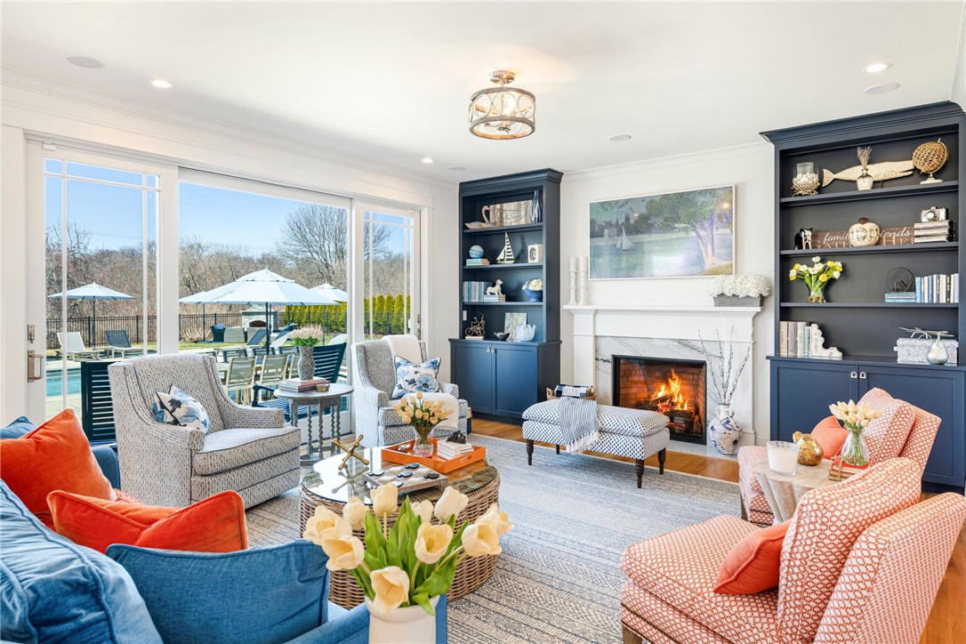Staged living room with blue built-ins, a fireplace, and glass doors overlooking the patio and pool.