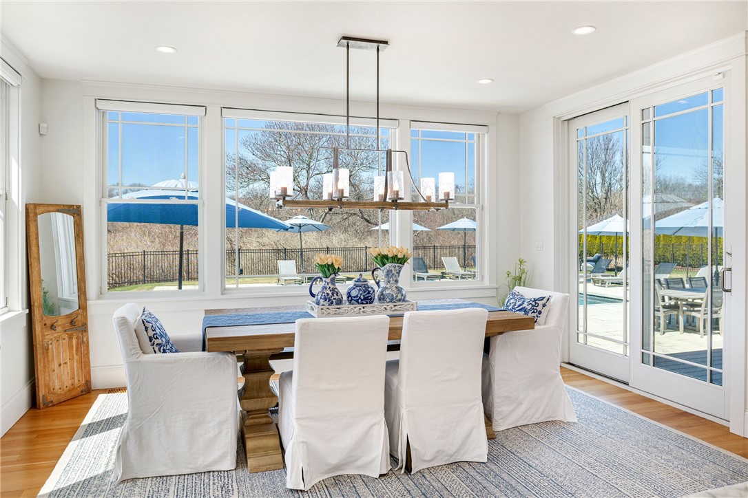 Dining room with white slipcovered chairs and large windows overlooking a poolside patio.