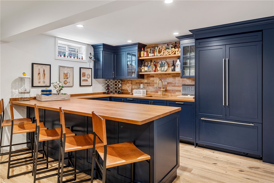 Kitchen with navy cabinets, a wood-topped island, bar stools, and a brick backsplash.
