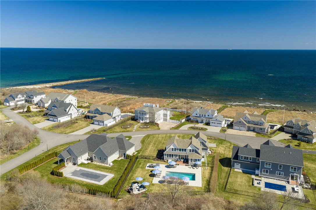 Aerial view of coastal homes along the ocean, with a swimming pool in the foreground.