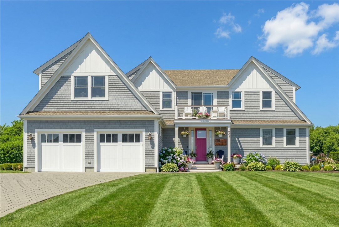 Gray shingle-style house with multiple gables, two garage doors, and a magenta front door.