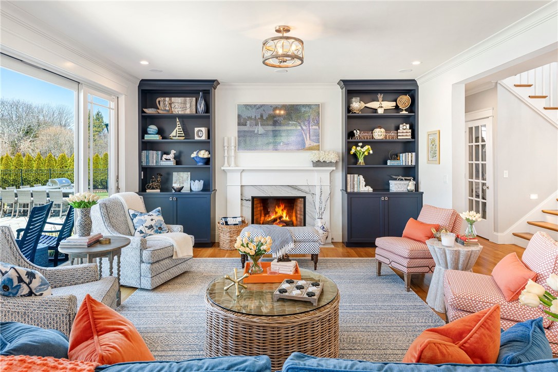 Living room with a white fireplace, navy built-in bookshelves, and windows overlooking a patio.