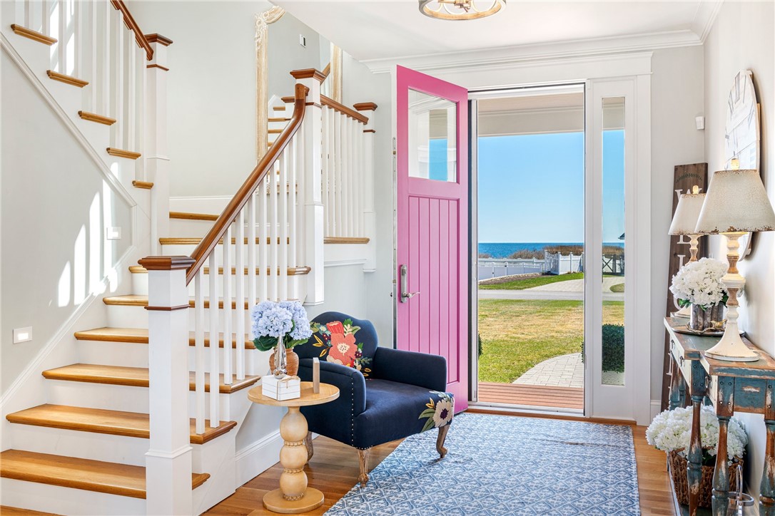 Entry foyer with a white staircase, pink front door, and ocean view.