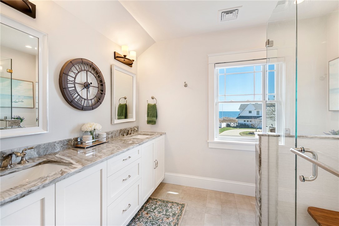 Bright bathroom vanity with marble-patterned countertop and ocean view through the window.