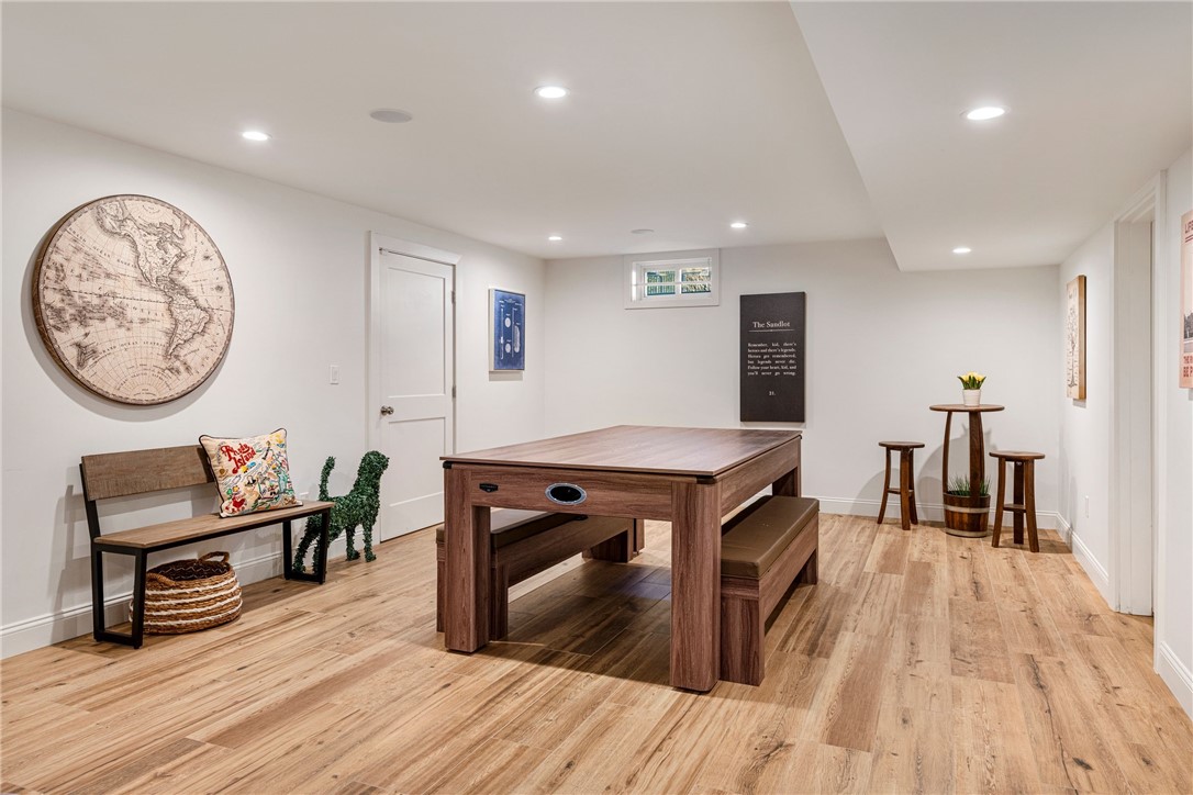 Basement game room with a wooden pool table, matching bench, and vintage map on the wall.