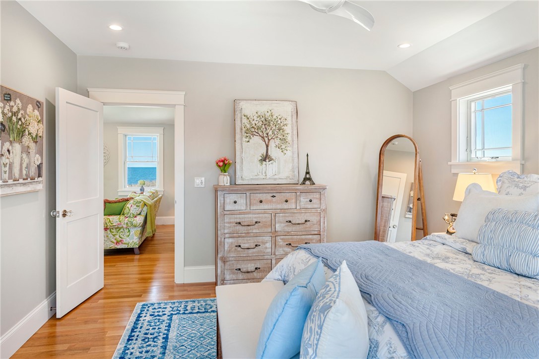 Bedroom with blue bedding and a dresser; ocean visible through the adjoining room.