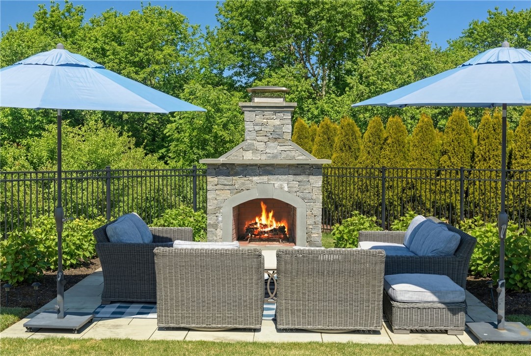 Outdoor patio with a stone fireplace, wicker seating, and blue umbrellas