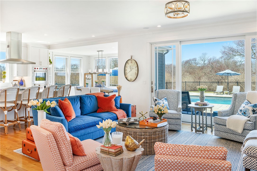 Open-plan living room with blue sofa and views through sliding doors to a swimming pool.