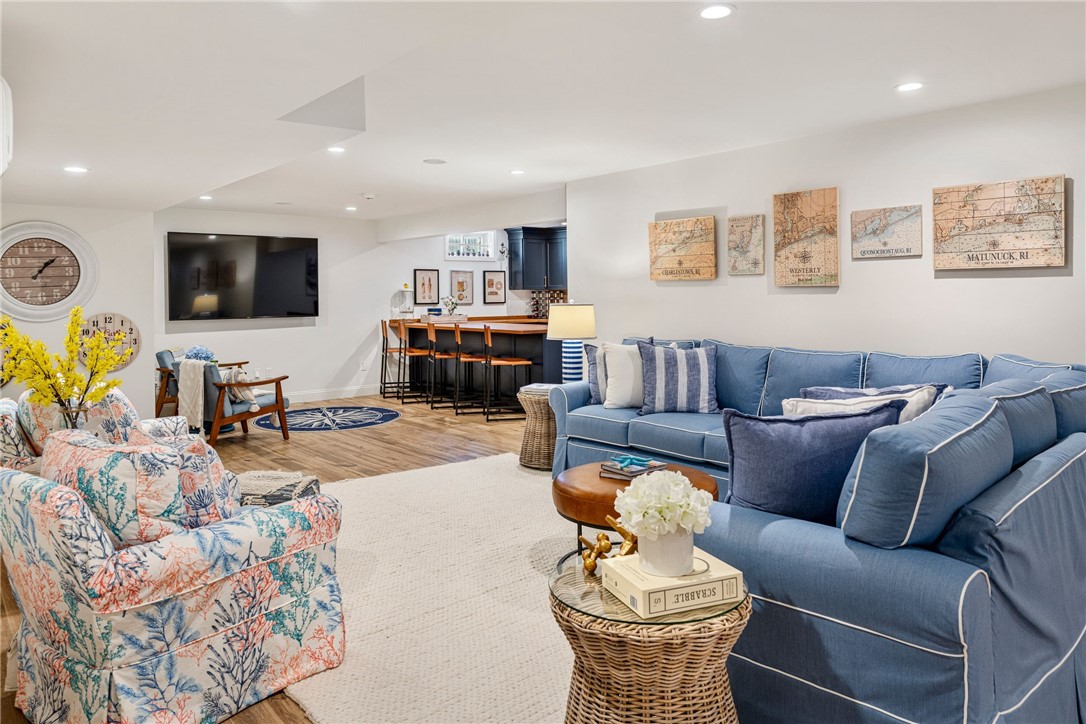Furnished living room with a blue sectional, floral armchair, and bar seating beneath coastal maps.