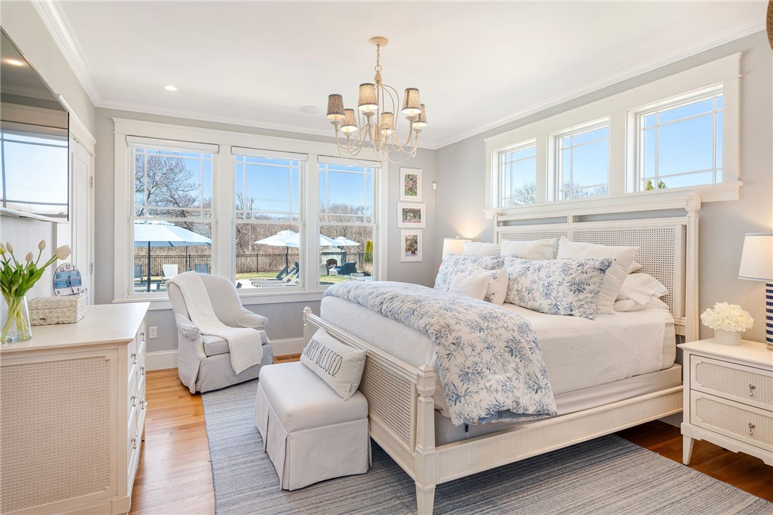 Bright bedroom with blue floral bedding and large windows overlooking a fenced patio.