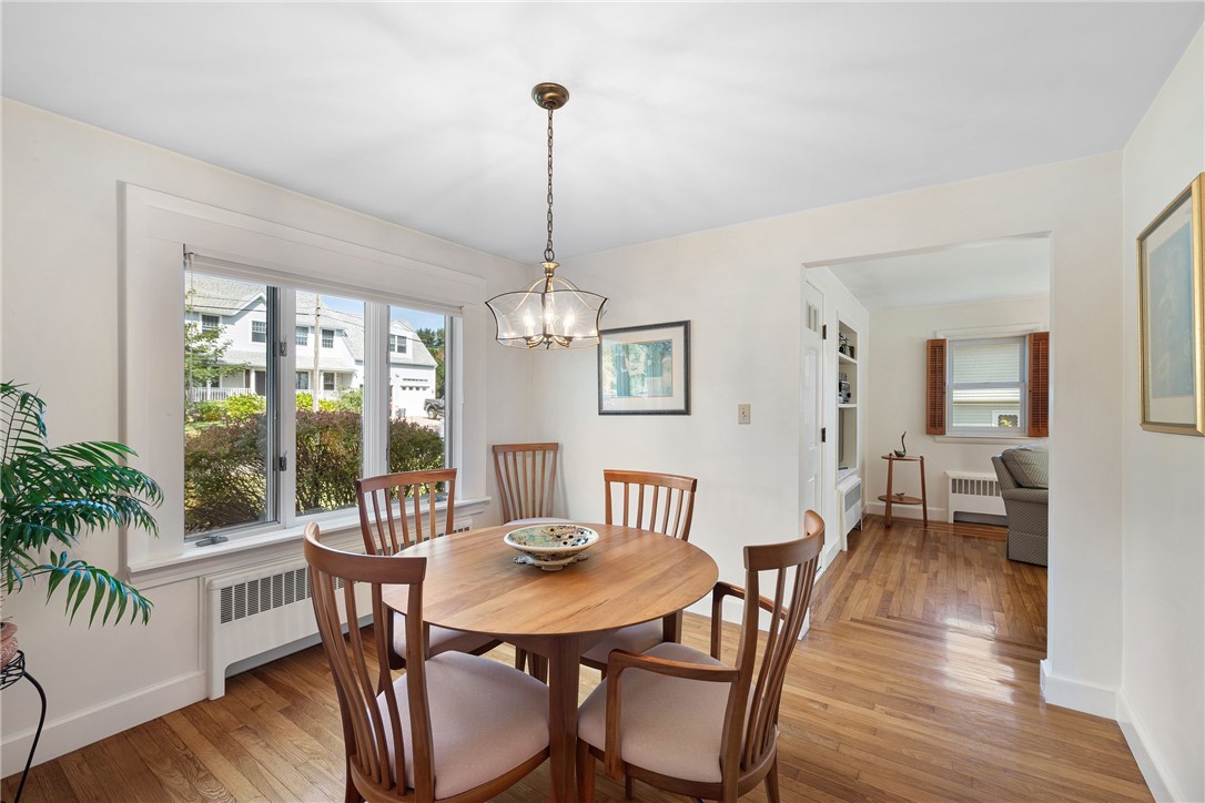 Dining room with a round wooden table, hardwood floors, and a large window.