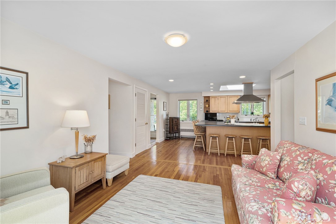 Living room with hardwood floors, a floral sofa, and an open kitchen with a breakfast bar.