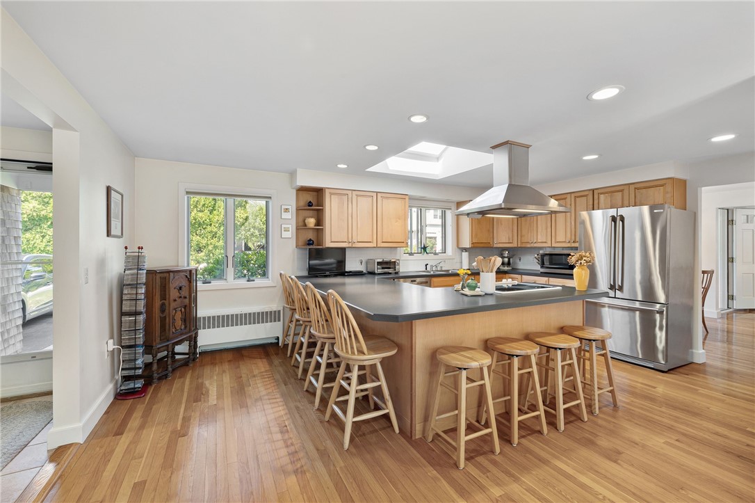 Kitchen with a large island, light wood cabinetry, stainless steel appliances, and a skylight.