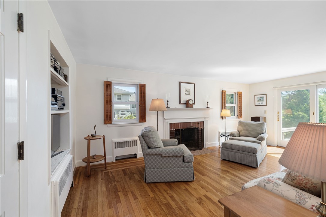 Living room with a white fireplace, hardwood floors, and two upholstered armchairs.