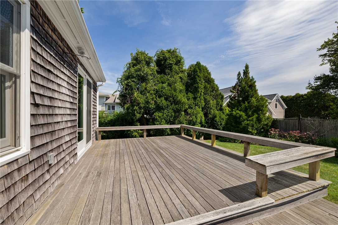 Spacious wood deck with built-in bench seating overlooking a leafy yard.