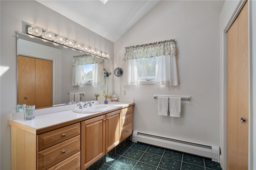 Bathroom with a long wood vanity, large mirror, and dark tile floor.