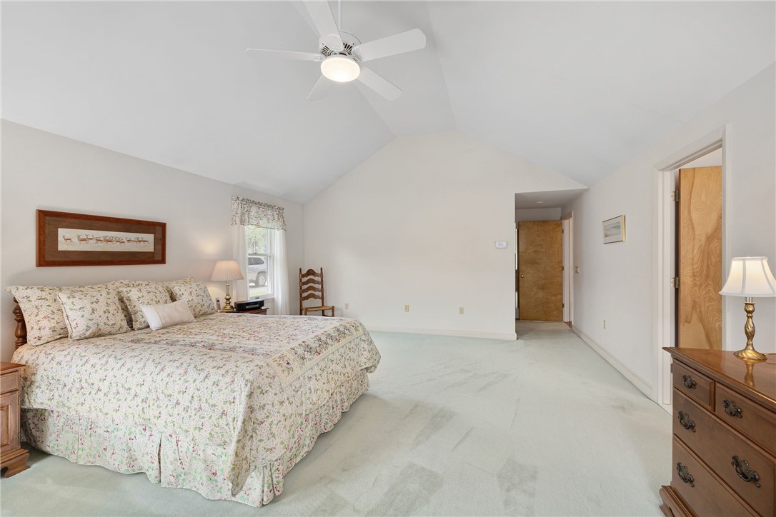 Spacious bedroom with a floral bedspread, vaulted ceiling, and pale carpet.