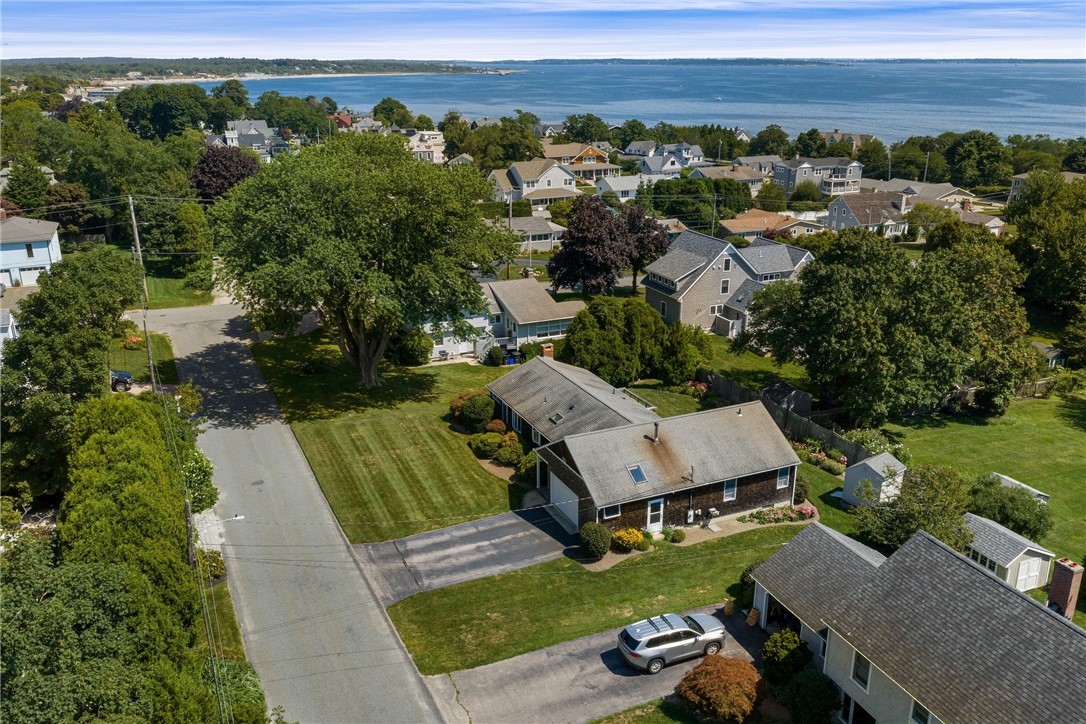 Aerial view of a gray-roofed house in a Narragansett neighborhood near the ocean.