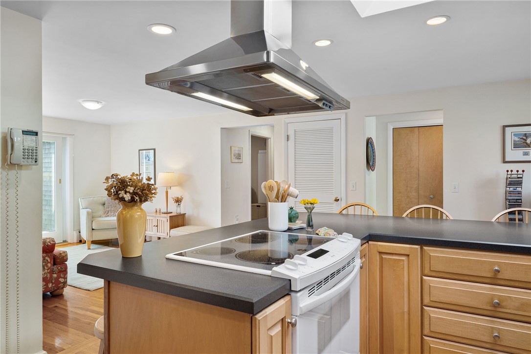 Kitchen with a large wood-cabinet island, electric cooktop, and suspended stainless-steel range hood.