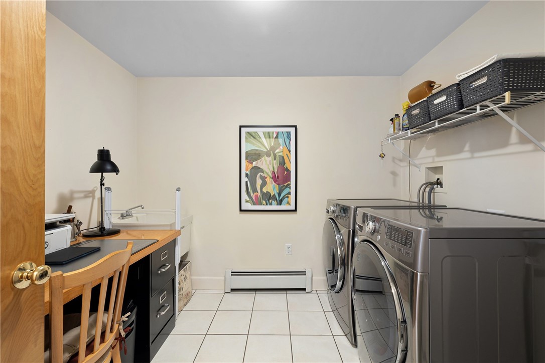 Laundry room with front-loading washer and dryer, desk, and overhead storage shelf.