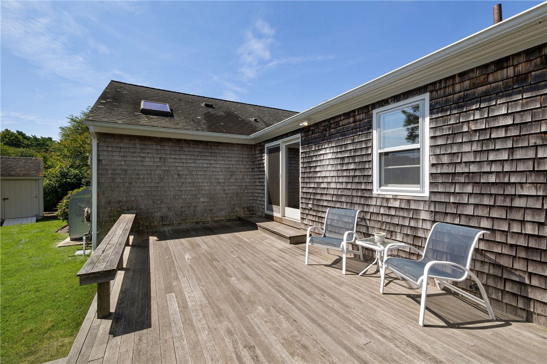 Wooden deck with two chairs beside a cedar-shingle home.