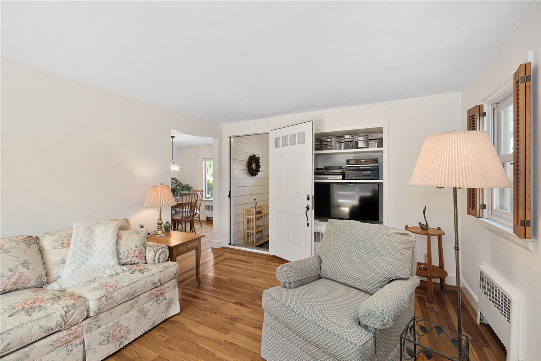Living room with hardwood floors, built-in media shelves, floral sofa, and shuttered windows.