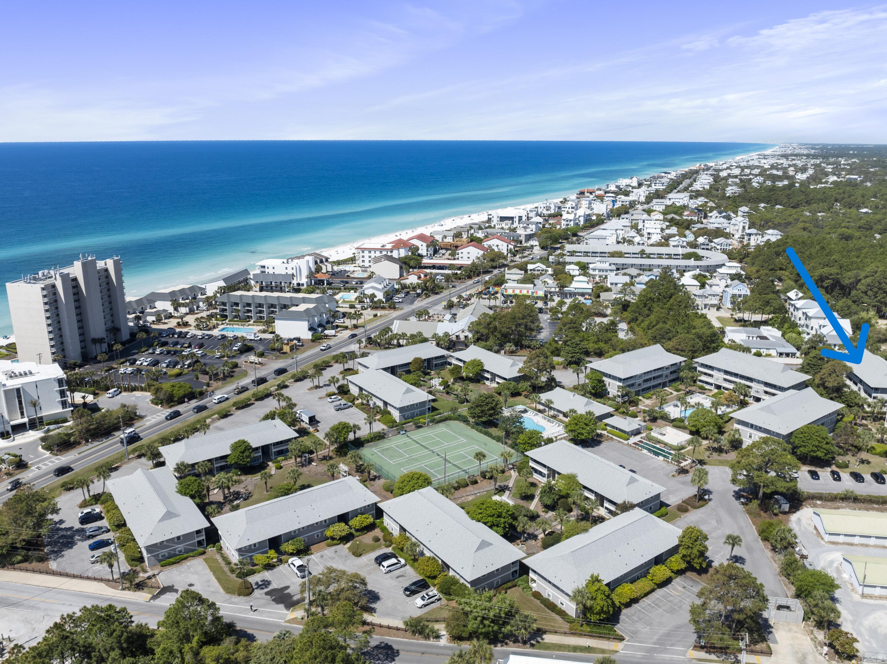 Aerial view of coastal condominiums beside the Gulf, with a blue arrow pointing to one building.