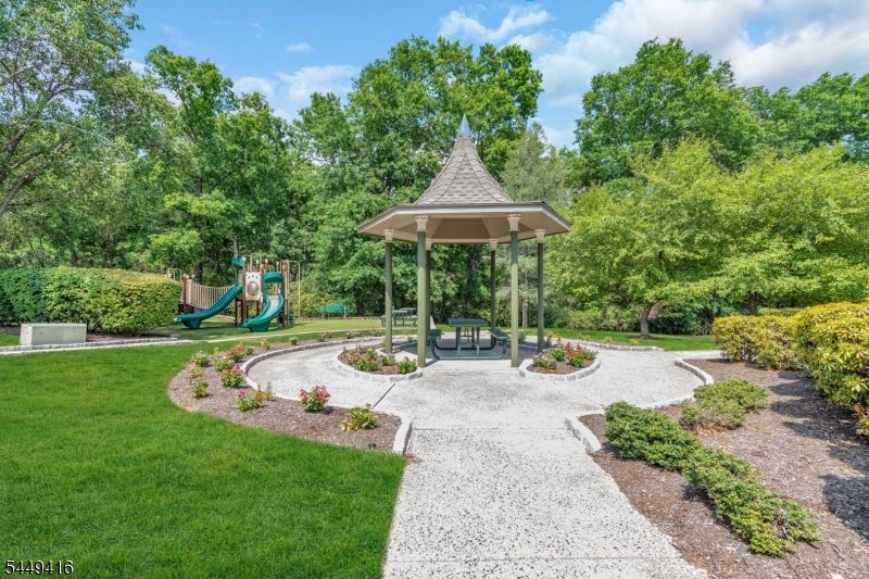 Outdoor gazebo with a picnic table, landscaped path, and playground nearby.