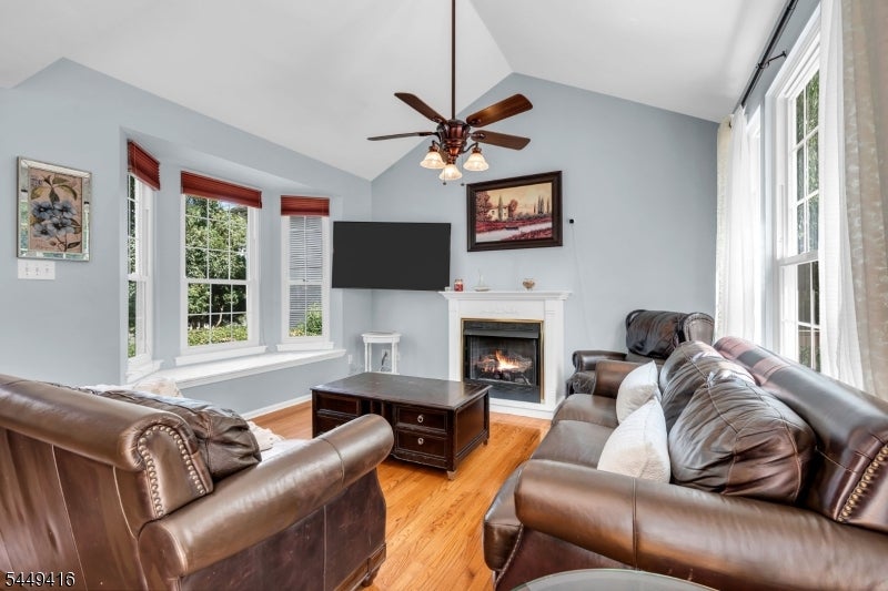 Living room with leather sofas, hardwood floors, a fireplace, and tall windows.