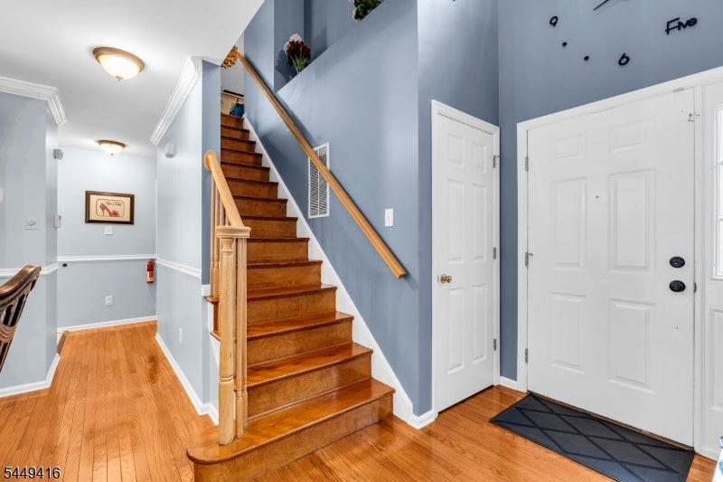 Entry foyer with a wooden staircase, blue walls, and hardwood floors.