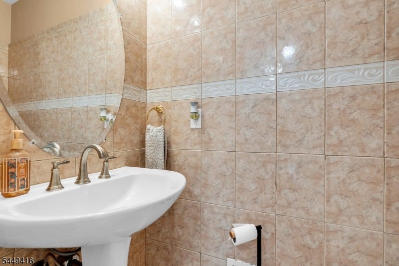 Bathroom with a white pedestal sink and beige tile walls with a decorative border.