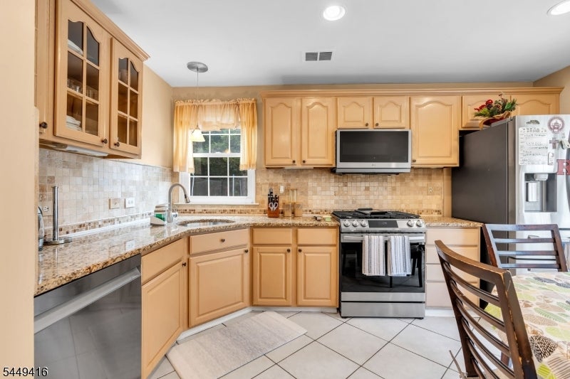 Kitchen with honey-colored cabinets, granite counters, and a window above the sink.