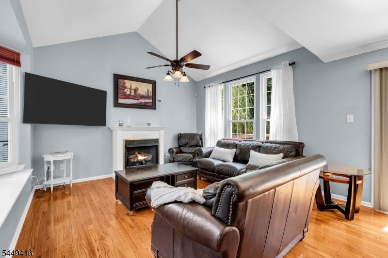 Living room with vaulted ceiling, leather seating, fireplace, and hardwood floors.
