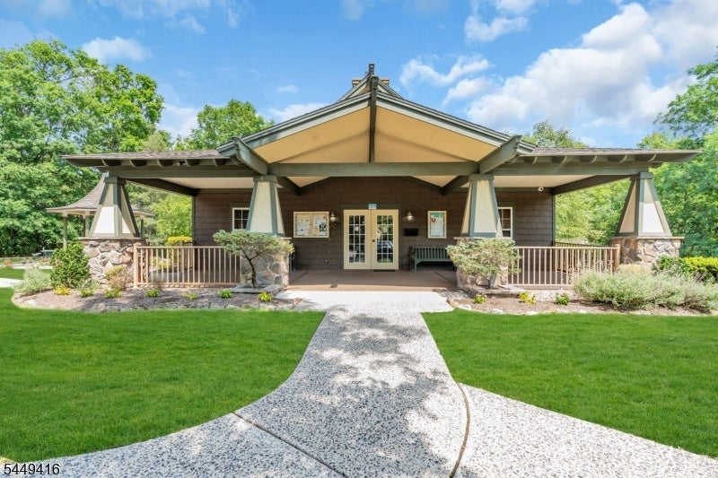 Pavilion-style building with a broad peaked roof, stone planters, and a curved walkway.