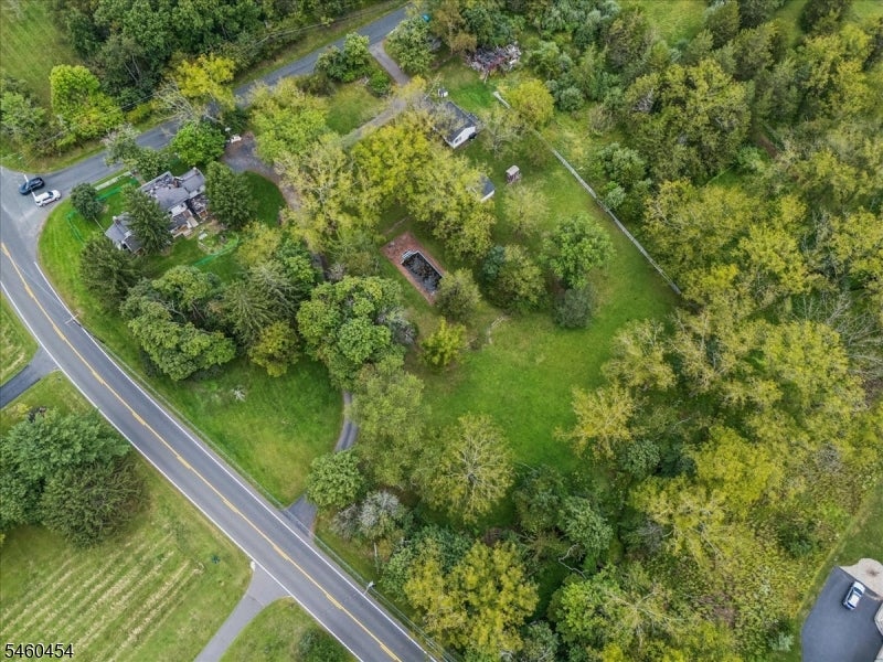 Aerial view of a wooded property with a house, outbuildings, and roadside frontage.