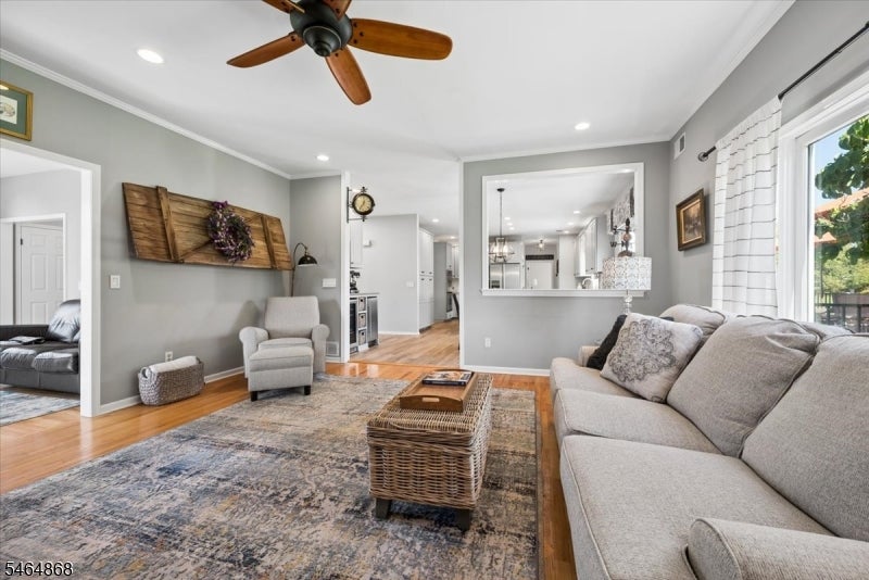 Living room with a gray sectional, patterned rug, wicker coffee table, and ceiling fan.