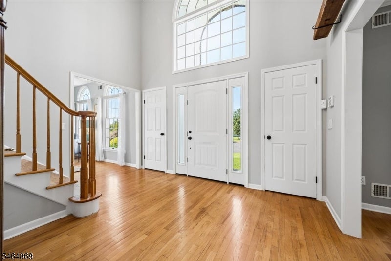 Two-story foyer with hardwood floors, a curved staircase, and a bright entry door.