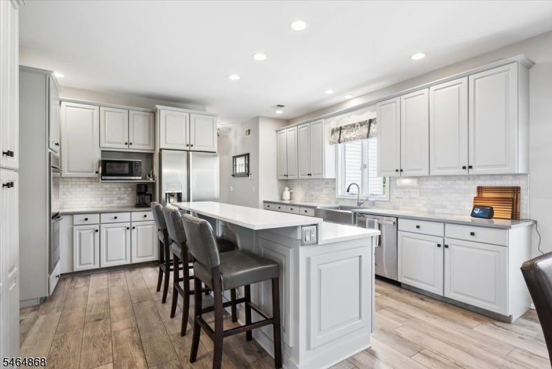 Bright kitchen with white cabinets, stainless appliances, and a large island with seating.